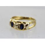 A DRESS RING SET WITH TWO SAPPHIRES, considered 18ct gold, size L 1/2