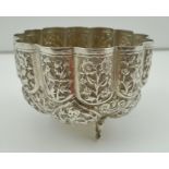 AN INDIAN WHITE METAL BOWL of lobed form, chased with panels of flowers, animals and birds, with