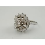 A LATE 20TH CENTURY TIERED DIAMOND CLUSTER RING, having central brilliant cut stone, surrounded by
