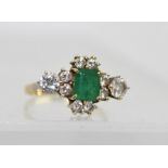 A DIAMOND AND EMERALD DRESS RING, the central facet cut emerald framed by eight small diamonds and