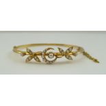 AN 18CT GOLD BANGLE decorated with a seed pearl inset crescent, flanked by seed pearl inset