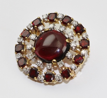 A DIAMOND SET BROOCH of "starburst" form, emanating from a central cabochon, the outer band set with