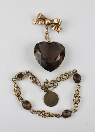 A 9CT GOLD BOW WITH PIN, suspending from it a heart shaped pendant, the facet cut stone,