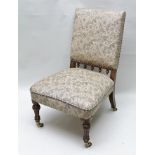 A VICTORIAN NURSING CHAIR having mahogany supports with brass castors, floral fabric upholstered