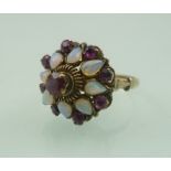 A RUBY AND OPAL CLUSTER RING, the central high set stone surrounded by eight pear shaped opals and