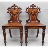 A PAIR OF 19TH CENTURY MAHOGANY HALL CHAIRS having carved shield backs and plank seats, on ring