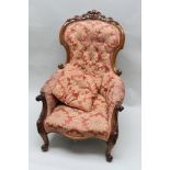 A VICTORIAN CARVED SHOW WOOD FRAMED ARMCHAIR, having buttoned back, on cabriole foreleg supports,