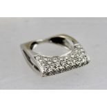 A CONTEMPORARY DESIGN DIAMOND SET RING in a white metal elliptical sided shank, size K and half