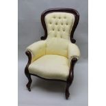 A VICTORIAN MAHOGANY FRAMED BUTTON BACK ARMCHAIR raised on cabriole fore supports, upholstered in
