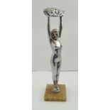 AN ART DECO CHROMED SCULPTURE, a naked woman standing, holding aloft a basket of flowers, raised