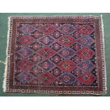 AN EASTERN RUG of overall geometric design, blue and red on dark ground, fringed and bordered, 157cm