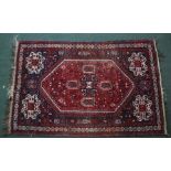 AN EASTERN RUG, having central red ground with stylised decoration, fringed and bordered, 152cm x