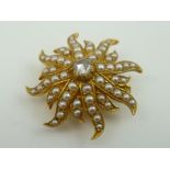 A STARBURST DESIGN BROOCH with pendant fitting, set with central diamond surrounded by seed