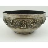 AN INDIAN WHITE METAL BOWL decorated with a raised band of deity roundels, stamped to the base "P.