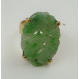 A 9CT GOLD DRESS RING inset carved Jade oval stone, carved with a bird amidst flowers