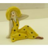 AN ART DECO POTTERY FIGURE of a seated woman of fashion in large brimmed sun hat, polychrome