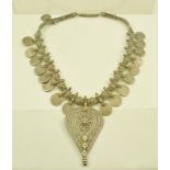 A BEDOUIN WHITE METAL NECKLACE decorated with coins, alternating with flower heads, suspending a