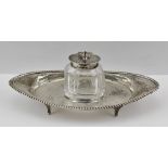 A VICTORIAN OVAL INKSTAND, having beaded rim, on four feet, with silver lidded glass well,