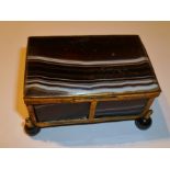 A CONTINENTAL GILT METAL TABLE BOX inset agate panels, raised on four turned ball feet, 7cm wide