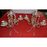 A PAIR OF SILVER PLATED CANDLESTICKS in the form of mythical creatures, winged, with scrolling