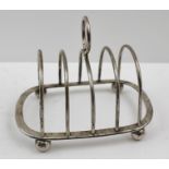 CARRINGTON & CO. A FOUR-SLICE SILVER TOAST RACK of wire form having central loop handle, raised on