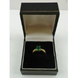 AN EMERALD RING, with diamonds set to the shanks, on an 18ct gold band, size M