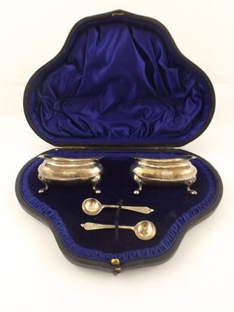 A PAIR OF OBLONG SILVER SALTS each having four pad feet, with two spoons monogrammed "H", London