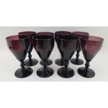 A SET OF EIGHT LATE VICTORIAN AMETHYST GLASS WINES, having tapering bowls, knopped stems on circular