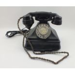 A BAKELITE TELEPHONE in black, rotating numeral dial, having retractable address panel to base,