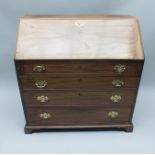 A GEORGIAN MAHOGANY BUREAU with well fitted interior, the fall-down writing slope supported on two