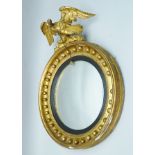 A 19TH CENTURY GILT FRAMED CONVEX WALL MIRROR, the ball mounted frame with an eagle mount, the eagle