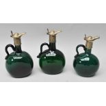 A GRADUATING TRIO OF GEORGIAN GREEN GLASS SPIRIT JUGS with plated mounts, (two with original