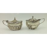 TWO VICTORIAN SILVER MUSTARD POTS, having embossed decoration with blue glass liners, Birmingham