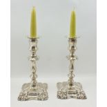 BARKER BROTHERS A PAIR OF GEORGE II DESIGN SILVER CANDLESTICKS, with removable drip pans, on waisted