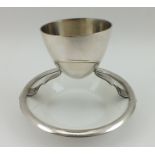 A CHRISTOPHER DRESSER DESIGN EGG CUP, of plated form with Royal Doulton white glazed ceramic dish