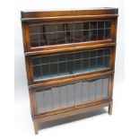 AN EARLY 20TH CENTURY OAK FINISHED GLOBE WERNICKE BRANDED THREE-TIER BOOKCASE, with lift-up leaded