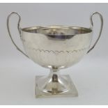 THOMAS BRADBURY & SONS LTD. A TWO-HANDLED SILVER TROPHY CUP, having leaf cast handles, on square