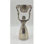 A SILVER WAGER CUP, cast as a lady, her full skirt being one of the cups, she holds aloft a