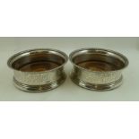 A PAIR OF GEORGE III SILVER BOTTLE COASTERS, with beaded rims, chased fruiting vine decoration, with