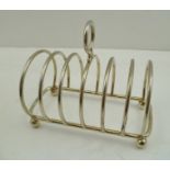 RICHARD WOODMAN BURBRIDGE (HARRODS LIMITED) A SIX-SLICE SILVER TOAST RACK, on four ball feet, London