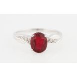 An 18ct white gold ruby and diamond ring, set with a central oval cut ruby, possibly treated,