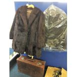 Two brown fur coats together with a suede coat and a brown leather suitcase.