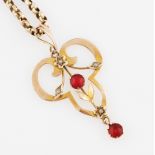 An Edwardian red paste and seed pearl pendant of open metalwork design, stamped 9ct, on a belcher