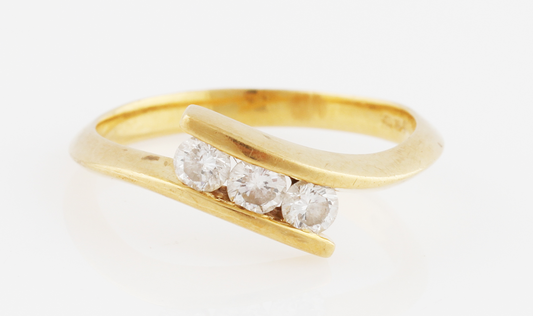 An 18ct yellow gold three stone diamond ring, bar set with three round brilliant cut diamonds in