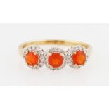 A 9ct yellow gold fire opal and diamond ring, set with three round cut fire opals surrounded by