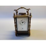 A brass cased carriage clock with bevel glass panels, turned column supports, white enamel dial by