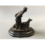 A bronze sculpture depicting hunter with dog, mounted on marble.