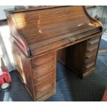 A Cutler oak roll top writing desk with eight drawers.