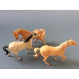 Three Beswick horses, two palomino, one grey.