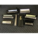 A selection of nine various harmonicas in cases.